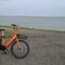 Een oranje deelfiets van Donkey Republic bij de Westerschelde